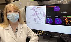 Peggi Angel sits next to a computer screen in her lab